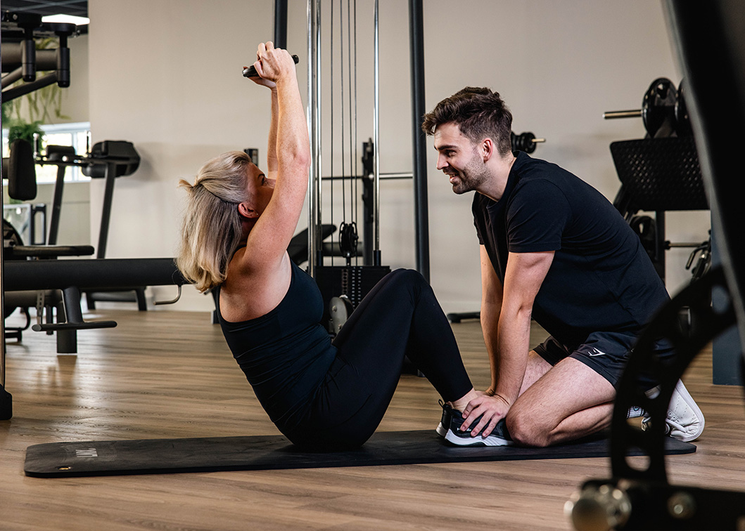 De coach helpt een cliënt met het doen van sit-ups